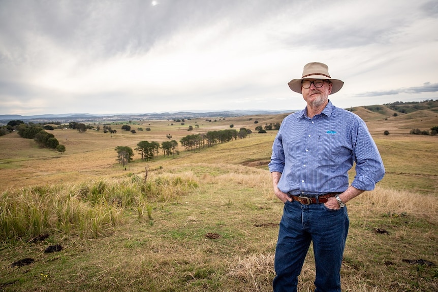 Farmer standing in a paddock with land in the background