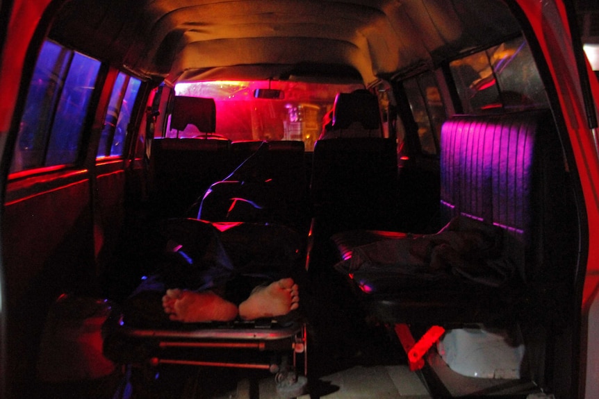 The body of Filipino meth user Carlito Gatchalian travels in the back of a mortuary service vehicle, feet visible.