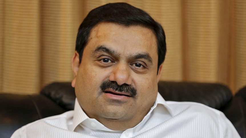 Gautam Adani, an Indian man with a moustache, stares into the camera with a serious expression. 