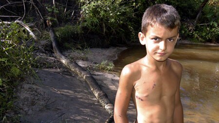 Matheus Pereira de Araujo, 8, stands in front of the anaconda that attacked him.