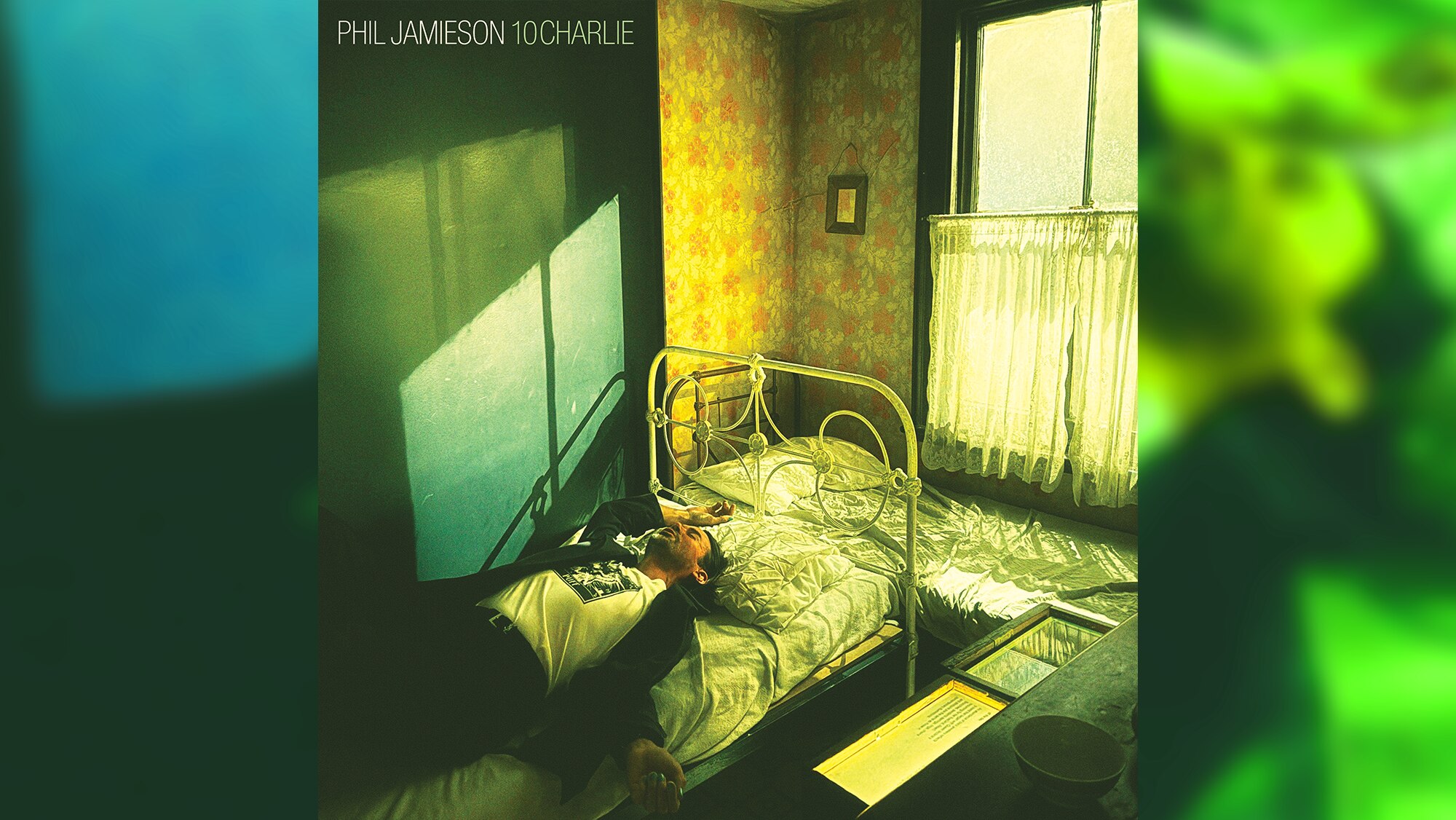 Yellow-green tinted image of Grinspoon's Phil Jamieson lying in a suit and tshirt on an old metal-frame bed by bedroom window
