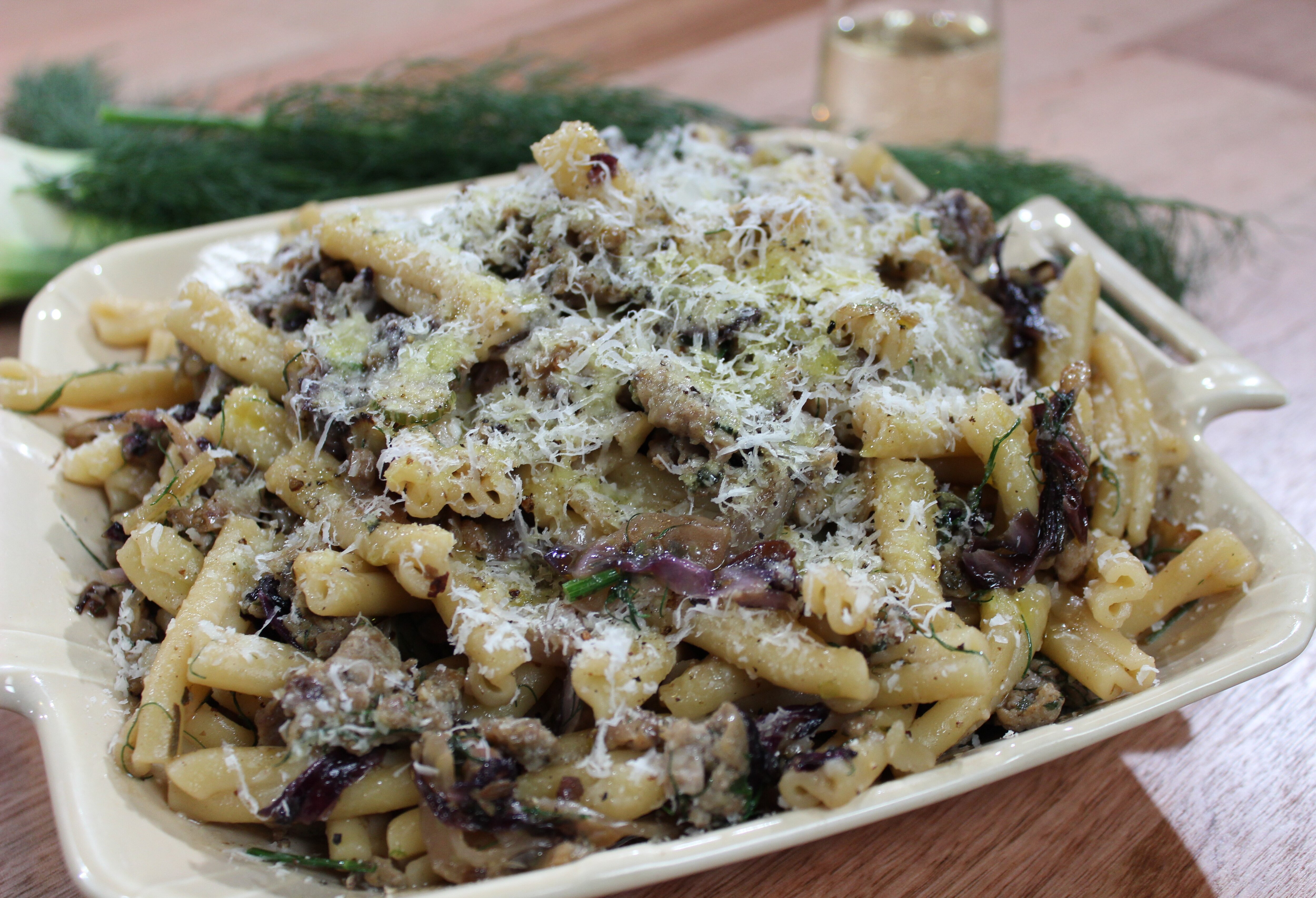 Una imagen de pasta con salchicha de cerdo e hinojo mezclada con hinojo salteado y achicoria en un bol. 