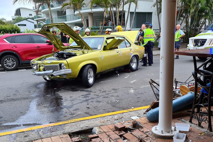 A wrecked car outside a restaurant with police and emergency services officers outside.