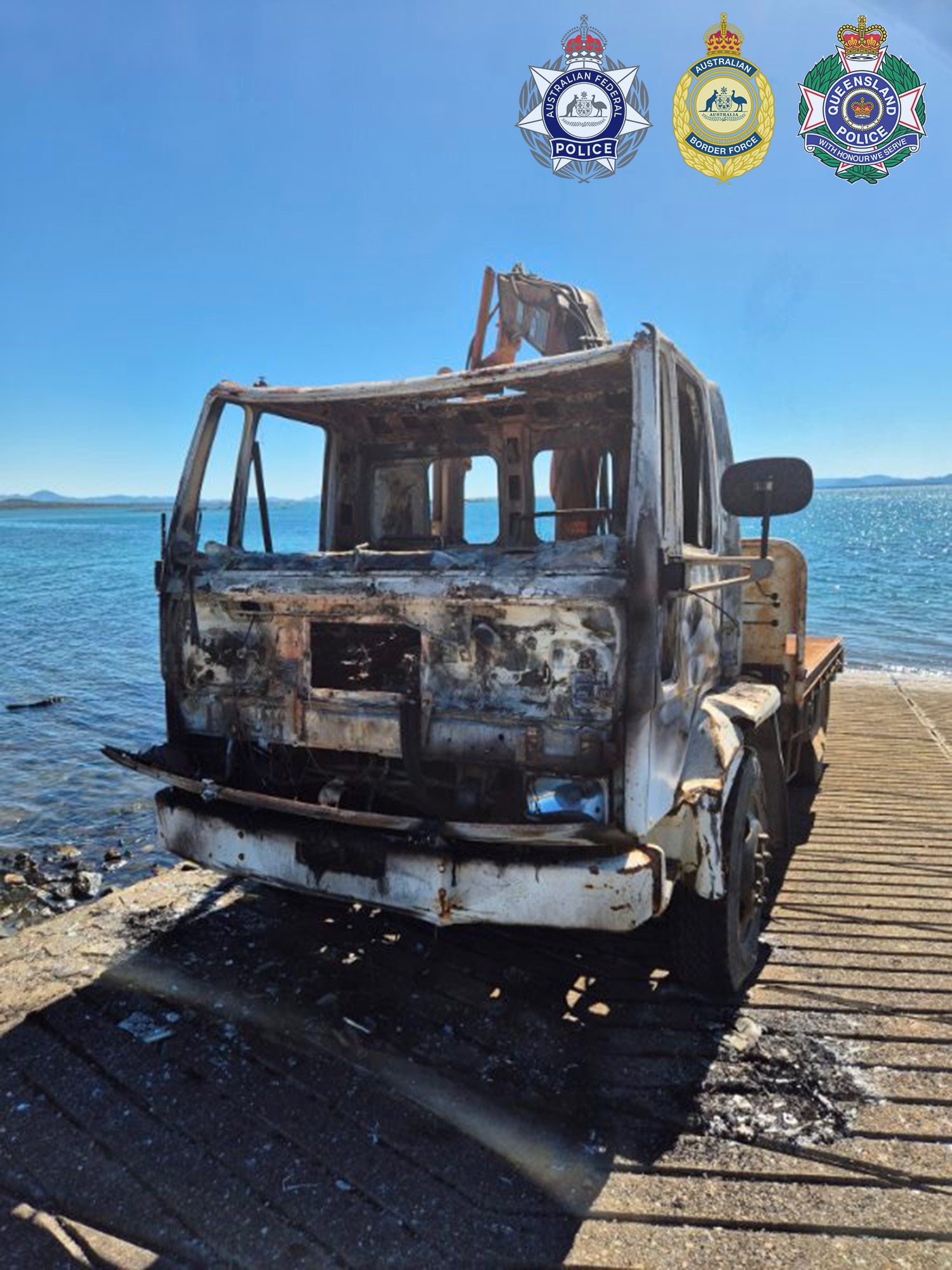 A burnt out truck at a boat ramp.