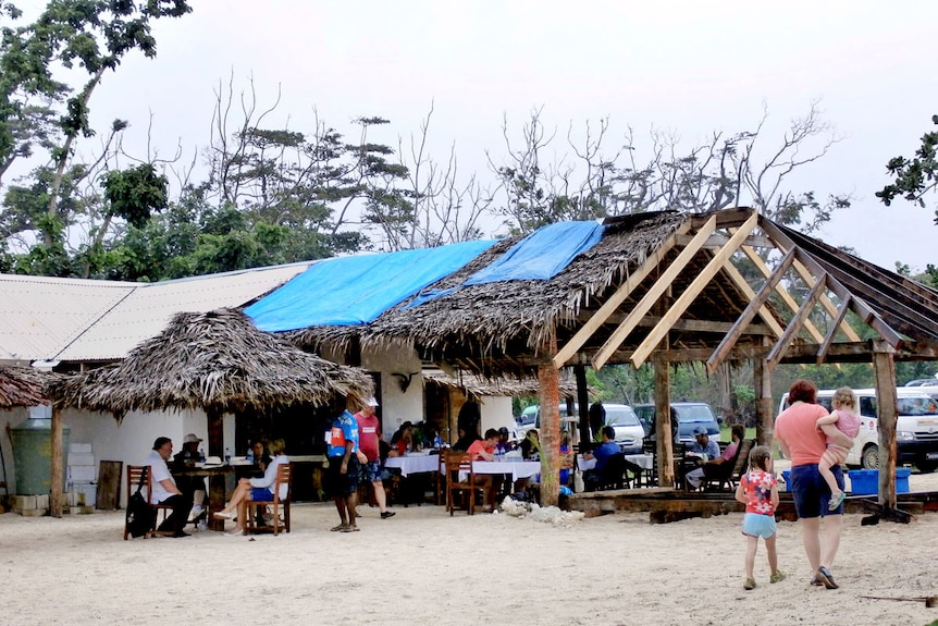 Tourists enjoying lunch at a beachside restaurant on the island of Efate.