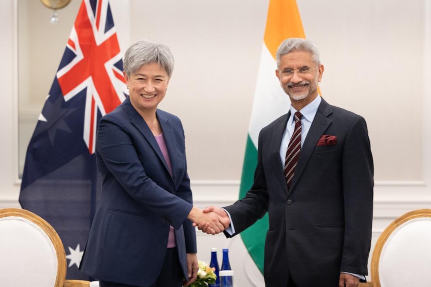 Penny Wong shakes the hand of Subrahmanyam Jaishankar with the Australian and Indian flags behind them 