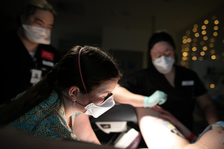 Bailey and Bella look down at a woman who is off-camera, giving birth.