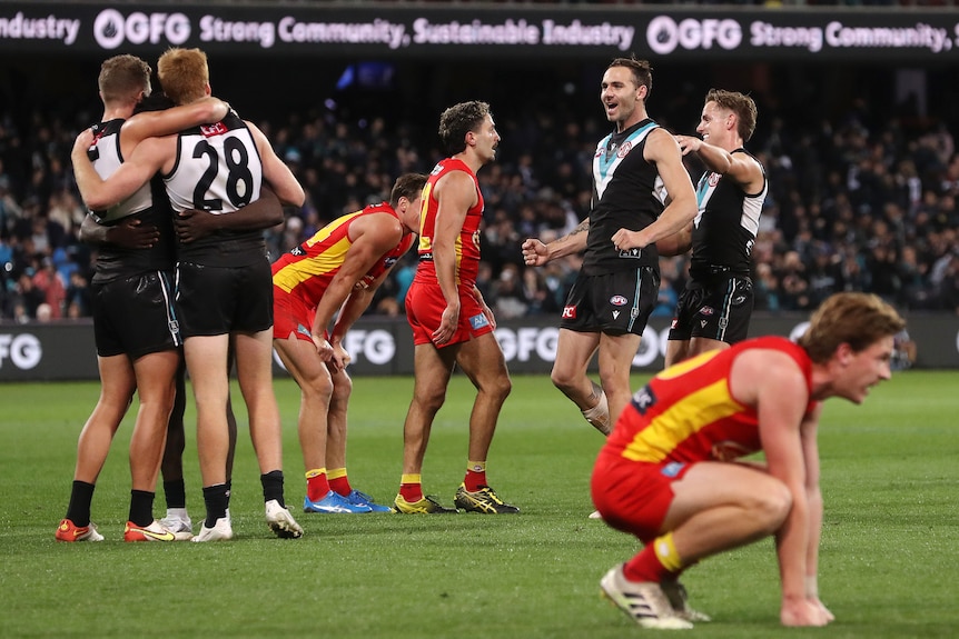 Los jugadores de Port Adelaide celebran una victoria mientras que los jugadores de Gold Coast parecen decepcionados