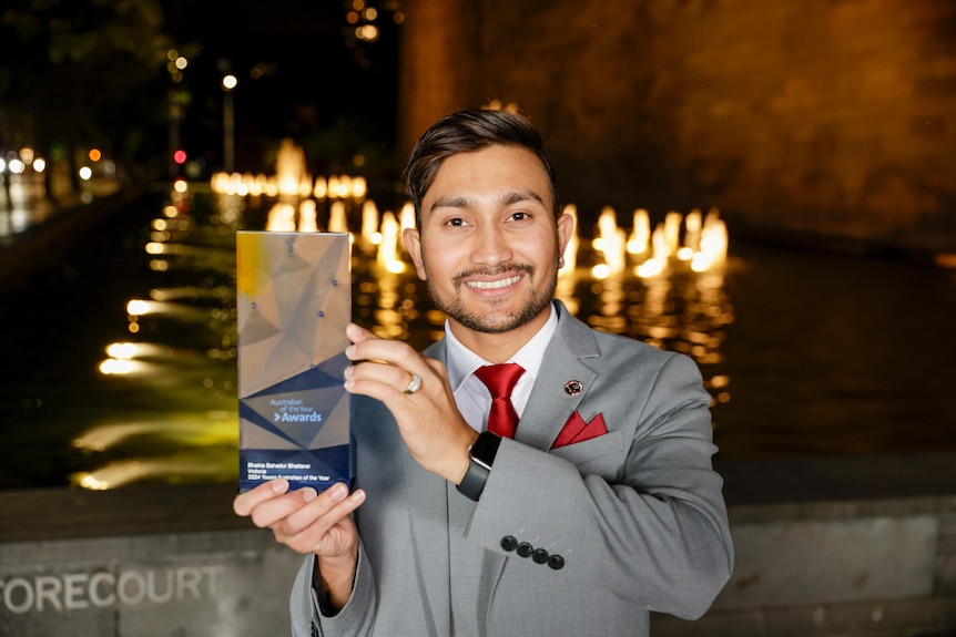 A man smiling at the camera holding an award