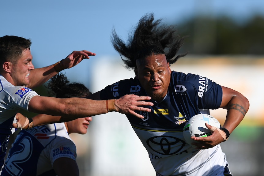 Luciano Leilua's hair flies around as he palms off an opponent while running with the ball