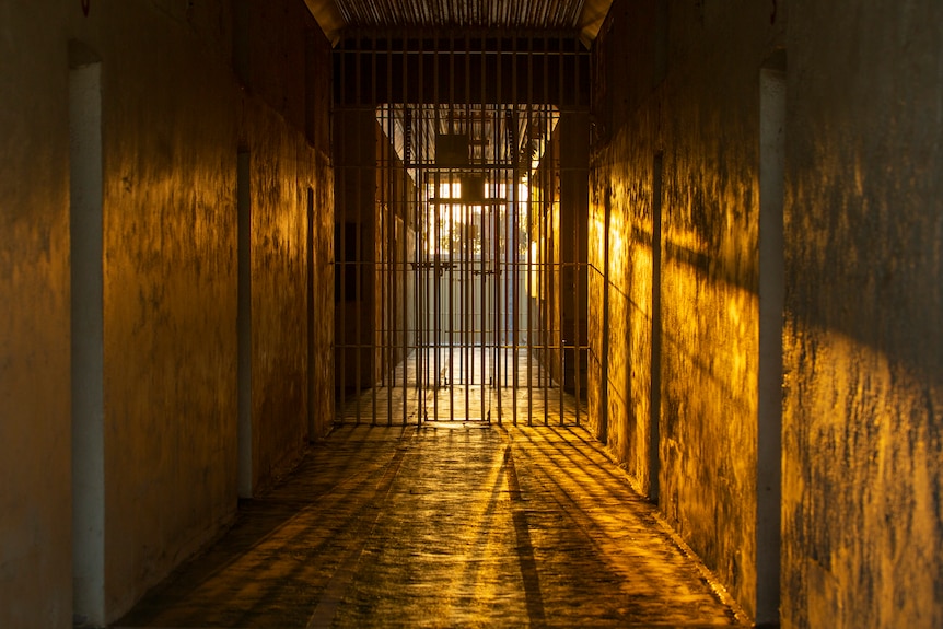 A gaol cell door with the setting sun shining through.