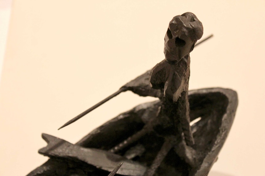 A close-up detail of a sculptural work featuring a fisherman and fisherwoman in a boat.