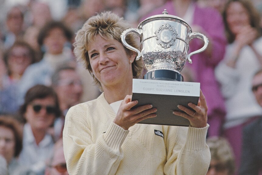 Chris Evert smiling while holding the French Open trophy in 1985 