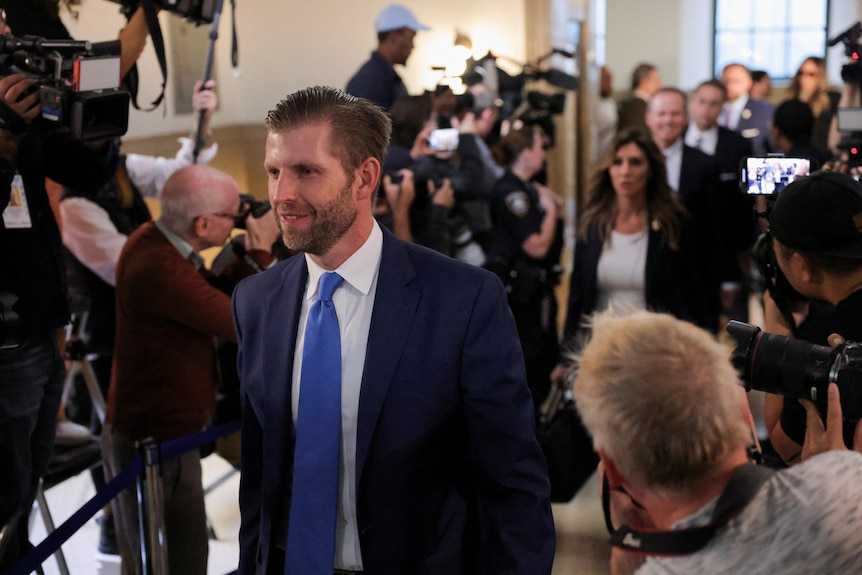 Eric Trump walks past a throng of photographers.