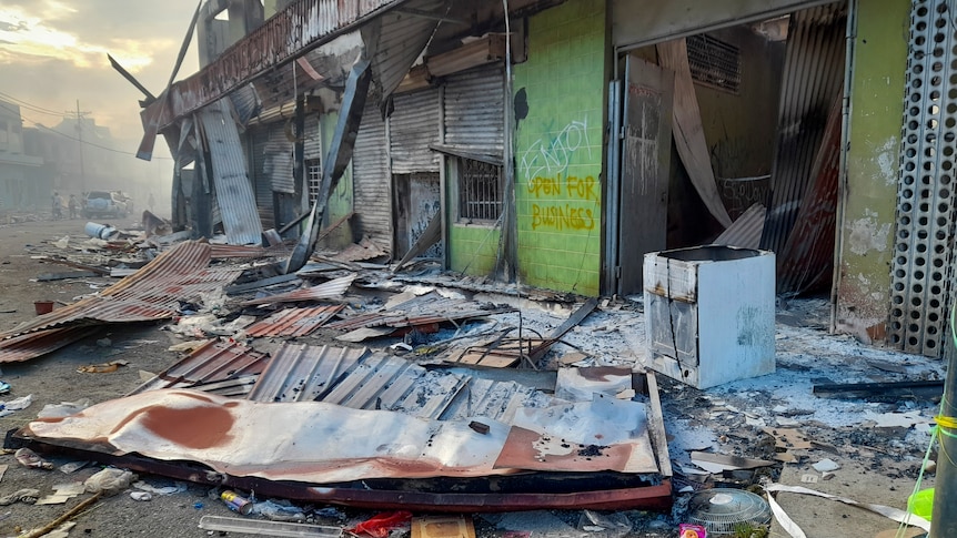 Debris lies on the street outside damaged shops in Chinatown, Honiara