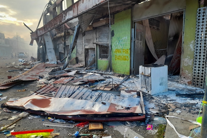 Debris lies on the street outside damaged shops in Chinatown, Honiara