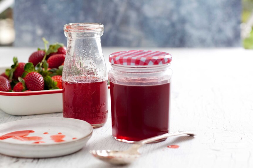 A bottle and a jar of strawberry syrup, for a story about strawberries.
