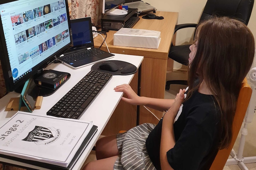 A primary school student studies at home using a laptop.