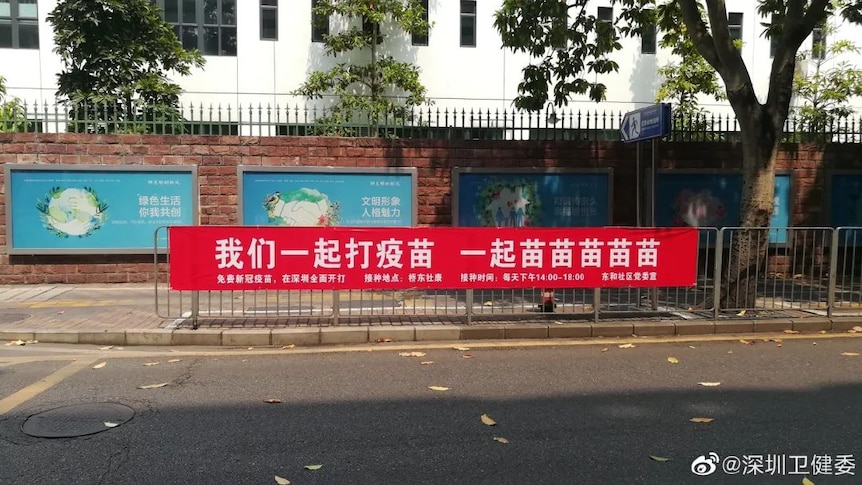 A red banner on the street says “Let’s get vaccinated together”.