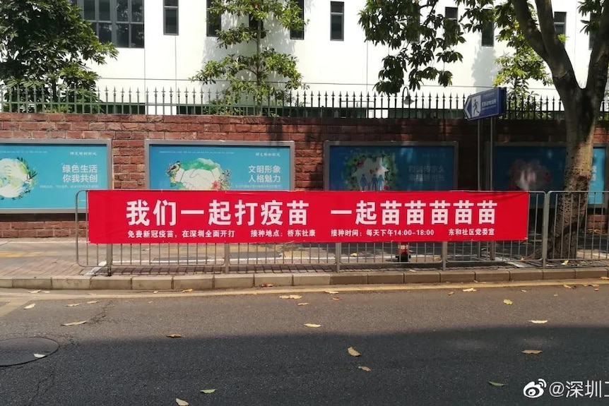 A red banner on the street says “Let’s get vaccinated together”.