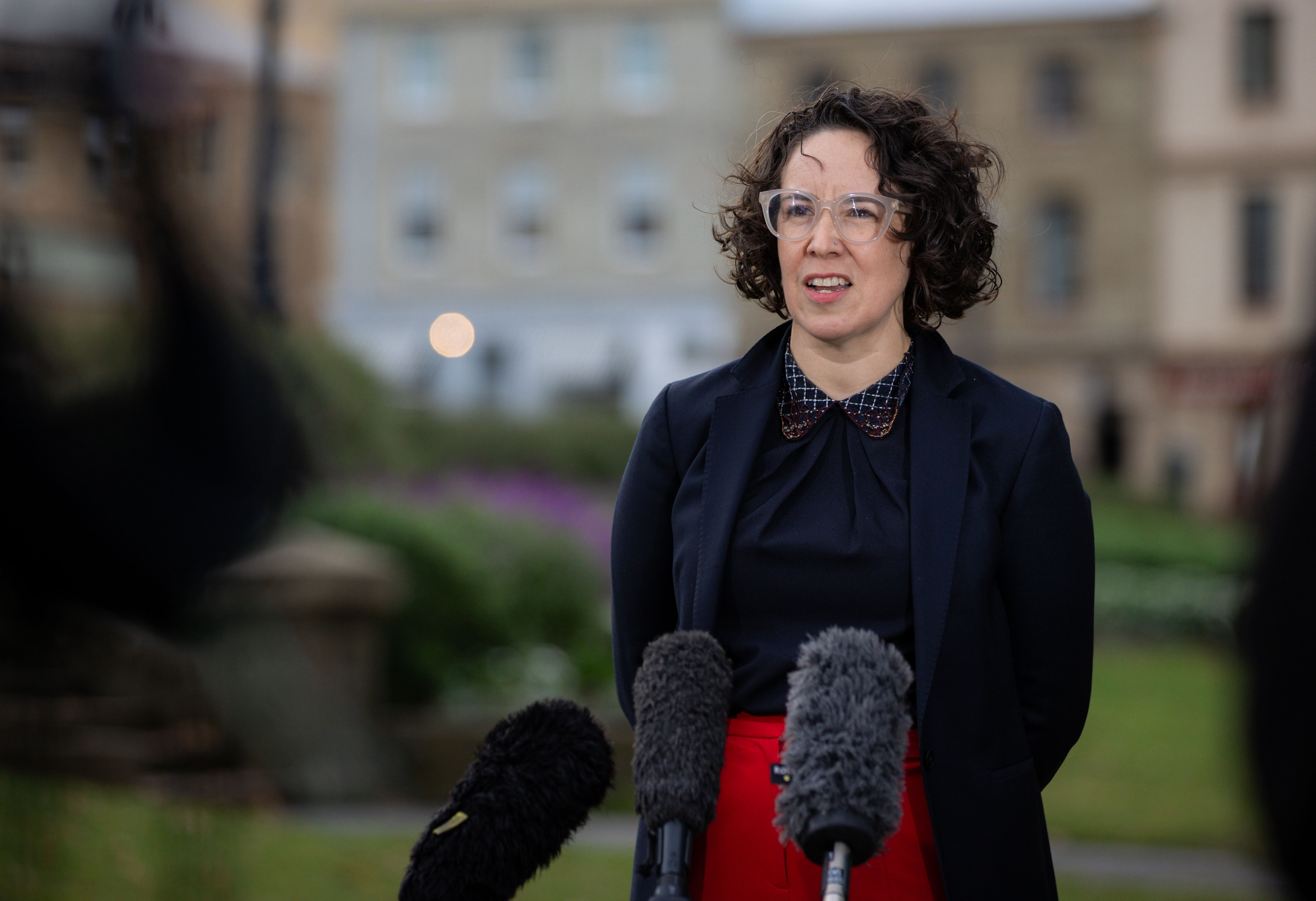 A woman with short black hair speaking to media.