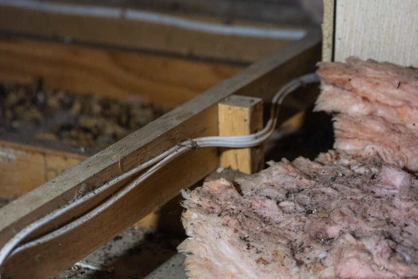 Pink insulation is seen in a roof cavity, along with electrical wiring.