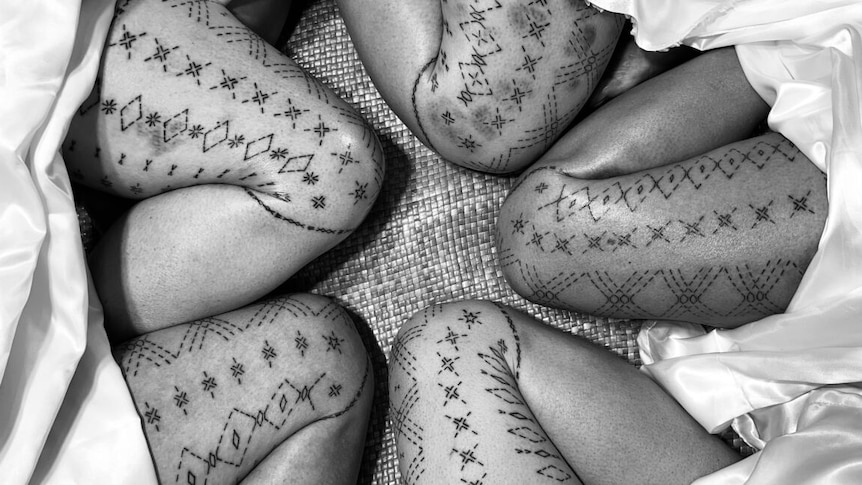 Black and white image of legs covered with Samoan tatau for women - the malu. 