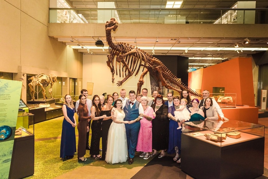 Couple standing with family under a dinosaur skeleton