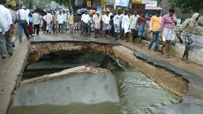 Indian villagers walk on damaged bridge