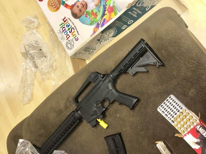 Packaging of a babies' toy lays on the floor, a semi-automatic rifle and ammunition is laid out on a seat.