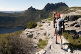 Two hikers with packs looking over Dove Lake at Cradle Mountain.
