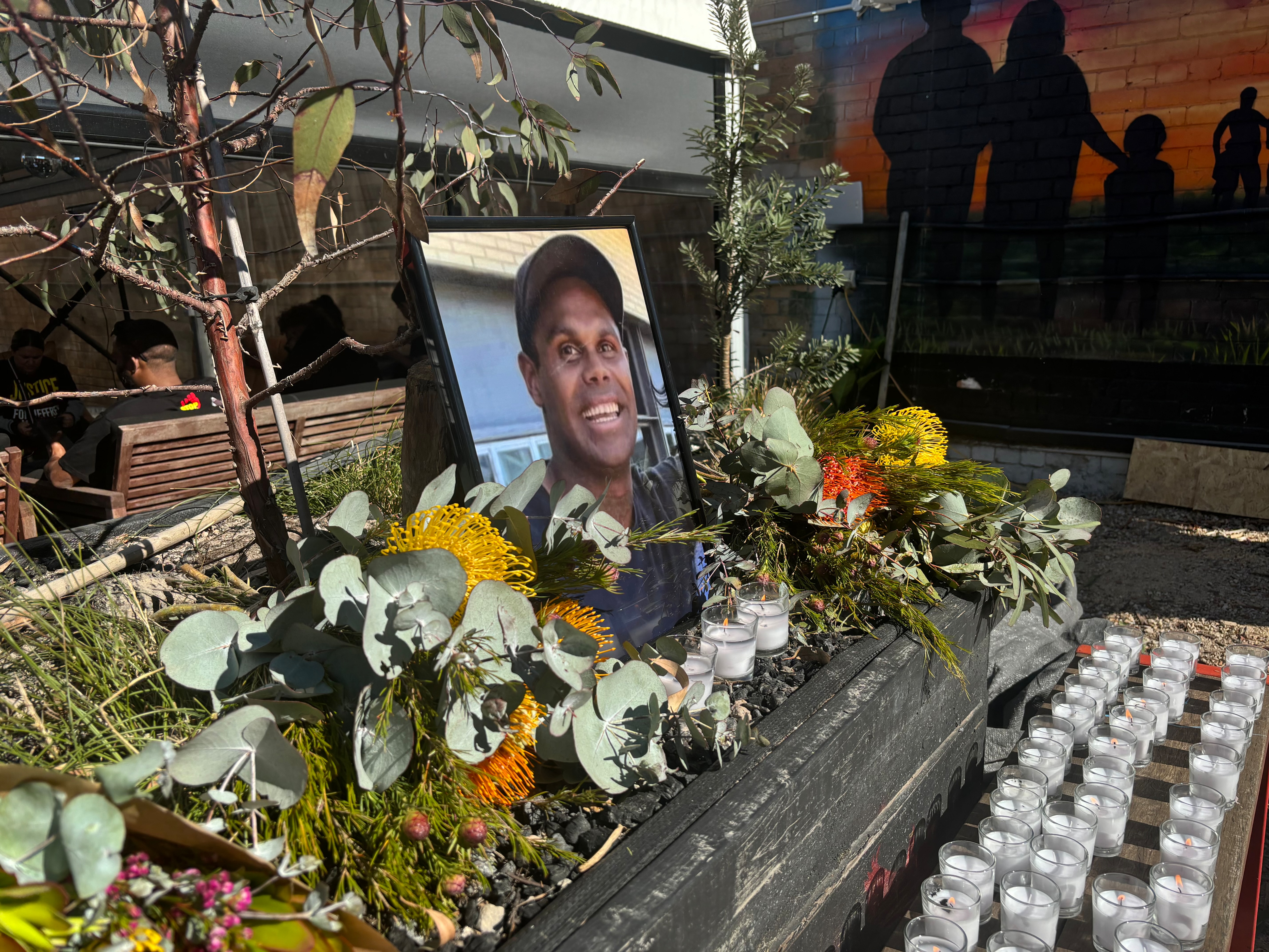 A memorial with candles and flowers around a picture of Jeffrey.
