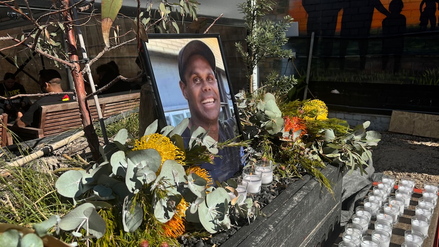 A memorial with candles and flowers around a picture of Jeffrey.