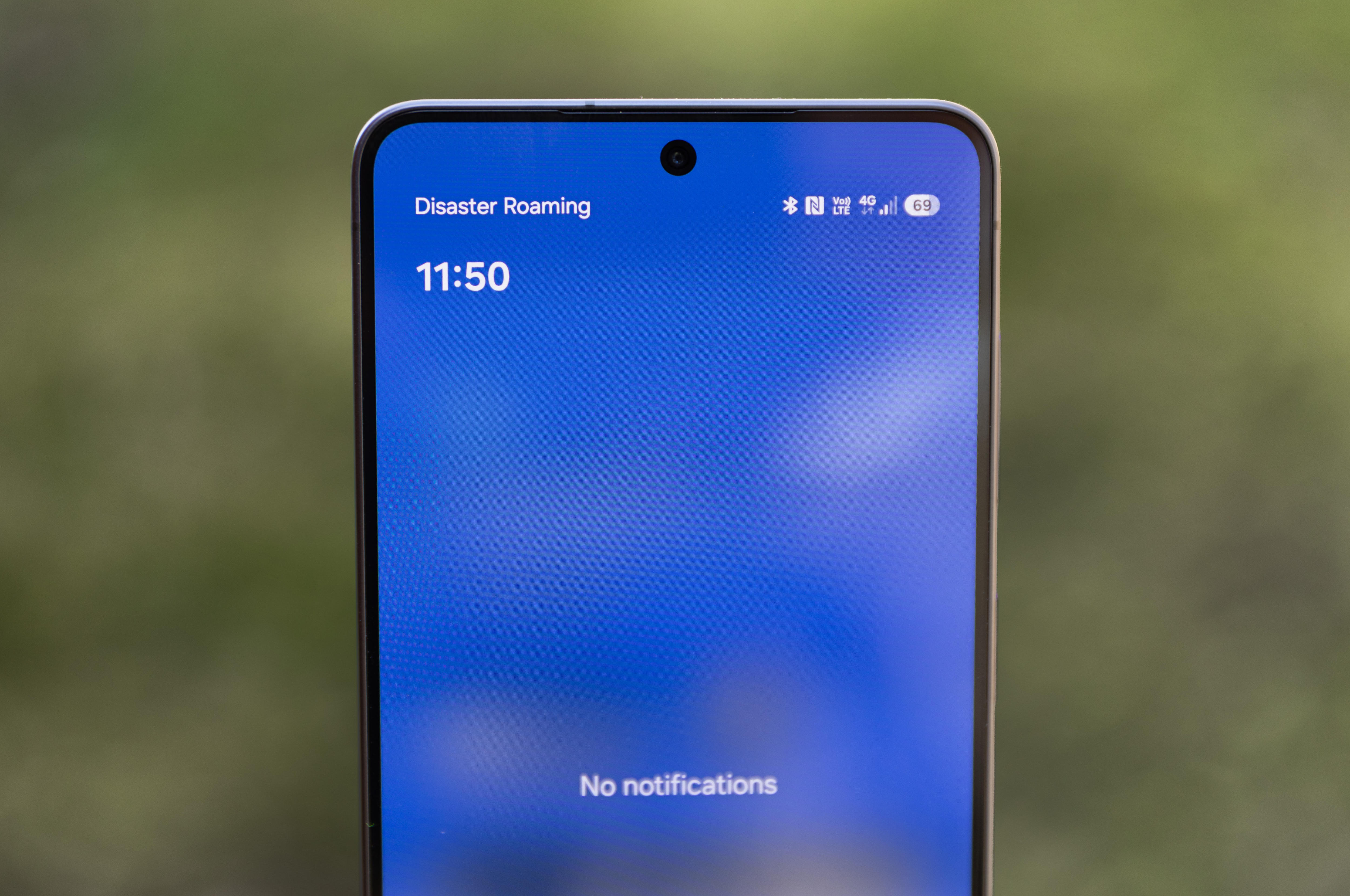 Close up of a mobile phone with a blue save screen, showing disaster roaming enabled in the top left hand corner