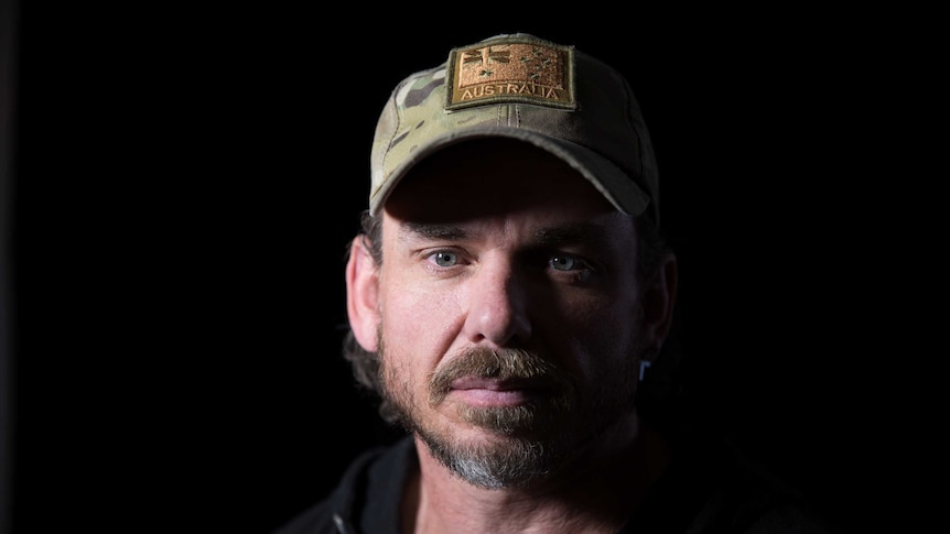 Commando Kevin Frost wearing a khaki cap with an embroidered Australian flag on the front.