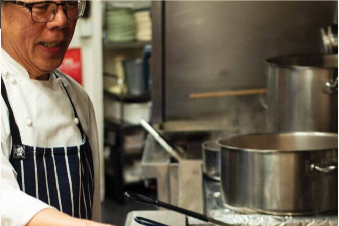 Tony Tan cooking a meat dish in the kitchen