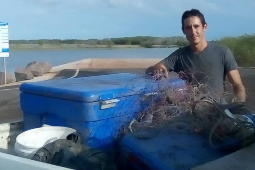 Graeme Talbot beside a ute filled with netting beside a river.