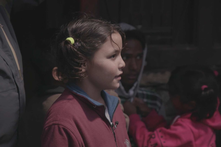 Devi stands waiting as other children talk with their parents.