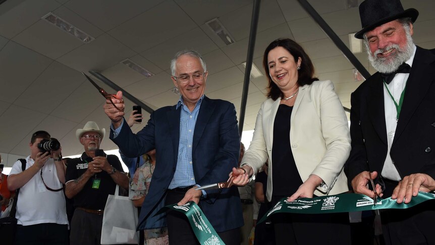 Australian Prime Minister Malcolm Turnbull gestures with scissors as the Queensland Premier Annastacia Palaszczuk.