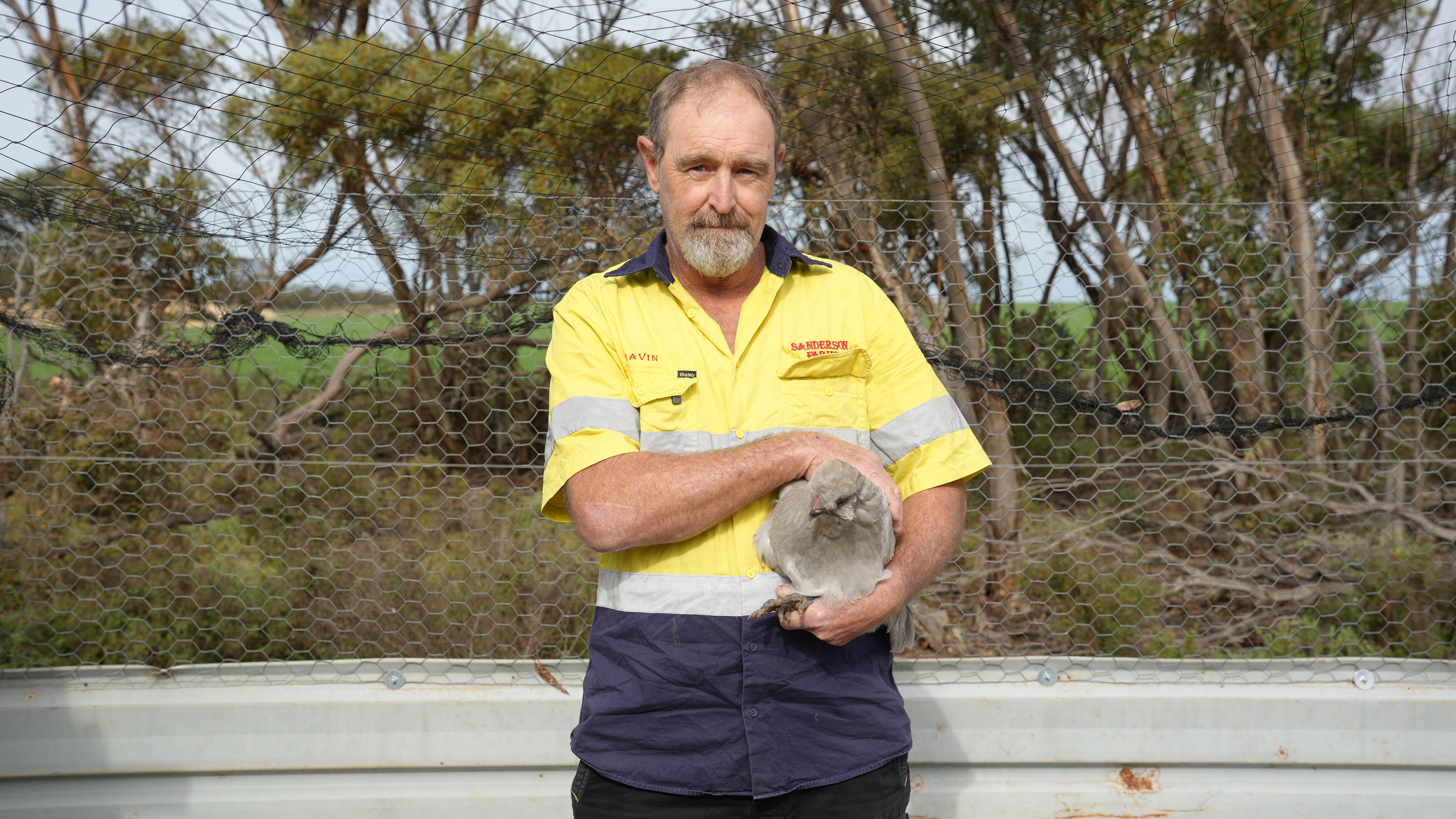 A man holding a chicken and looking at camera
