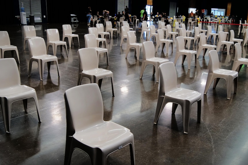 Dozens of empty chairs in rows inside a big hall