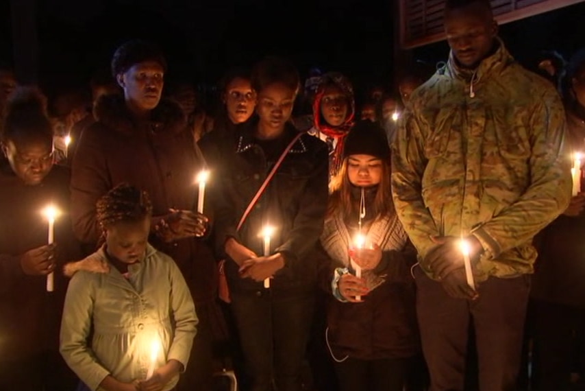 A group of children from the South Sudanese community holding candles at night.