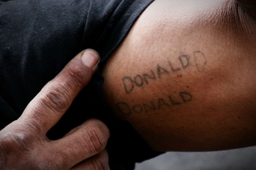A man's bicep with the word 'Donald' tattoed on it twice