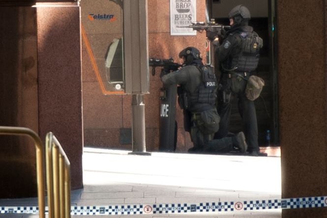 NSW Police State Protection Group members take up a position and point their weapons.