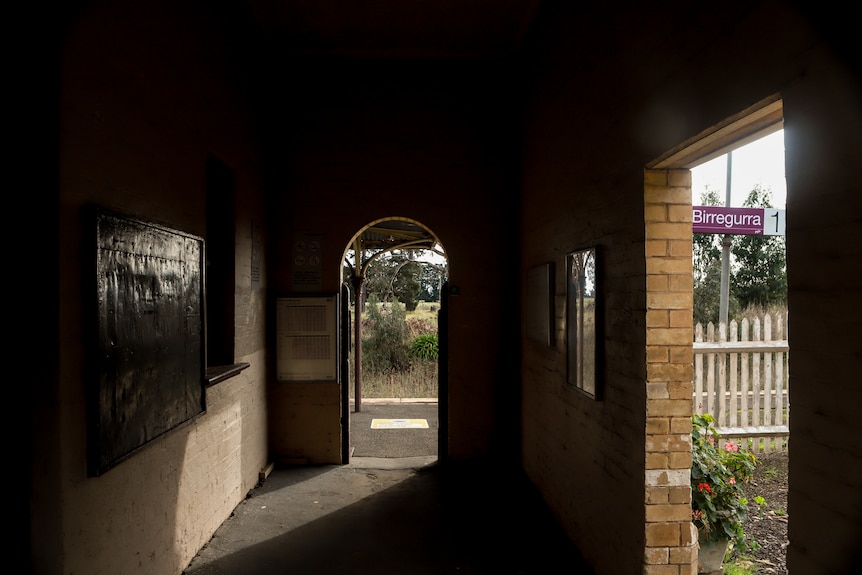 Lights streams into the entrance of a train station with a sign that reads Birregurra visible 