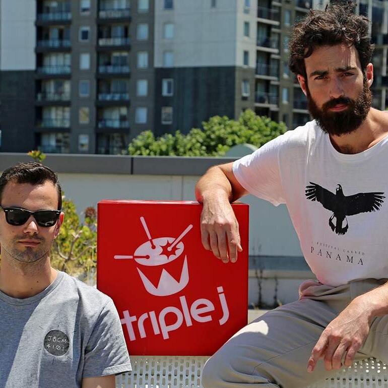 Photograph of Tom Iansek and Tom Snowdon sitting on a bench with a triple j logo.