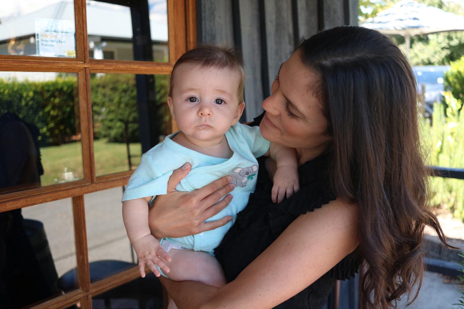 A woman holds a baby for a story on avoiding skincare products with food in them for eczema