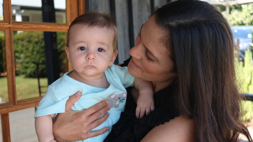 A woman holds a baby for a story on avoiding skincare products with food in them for eczema