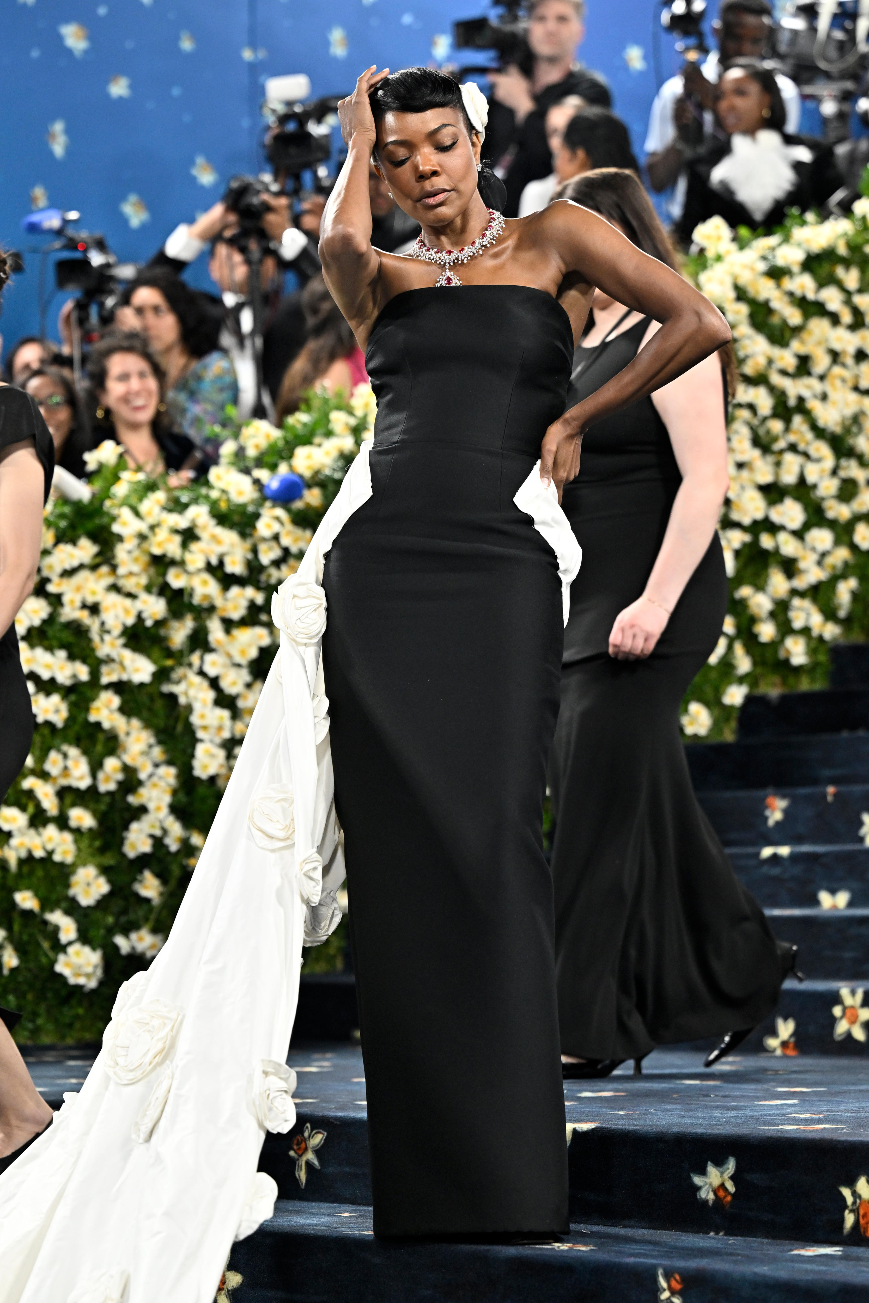 Gabrielle Union wearing a strapless black gown with a white train from the hips and white flowers in her hair