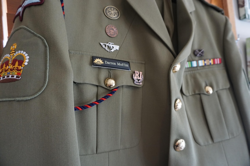 A close up image of a green army uniform and the name 'darren moffitt' appears on the badge.